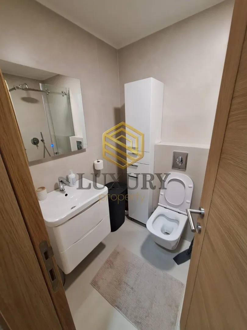 Modern bathroom equipped with a sink, toilet, and shower cabin.