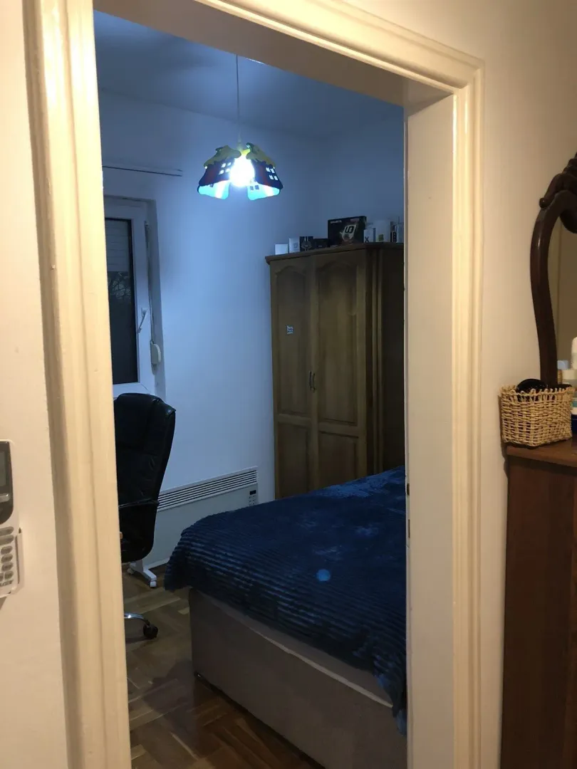 A bedroom with a bed and wardrobe viewed through a doorway.