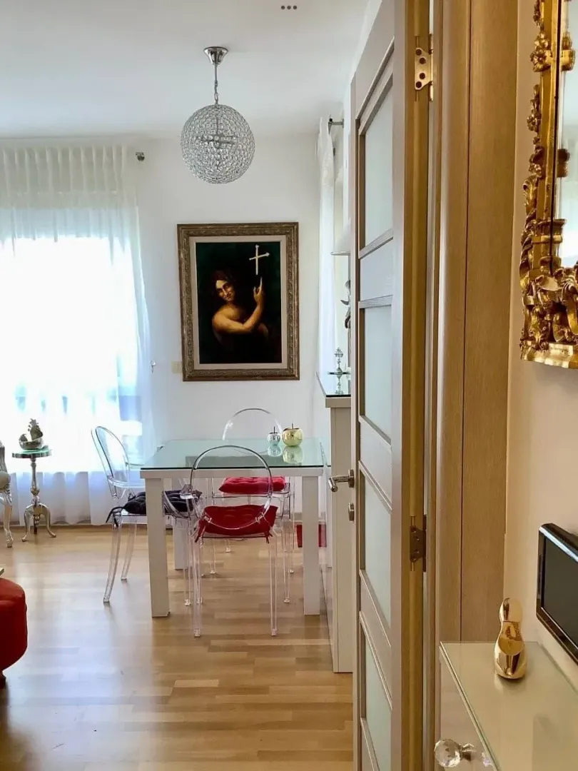 Dnevni boravak sa trpezarijskim stolom i staklenim stolicama.