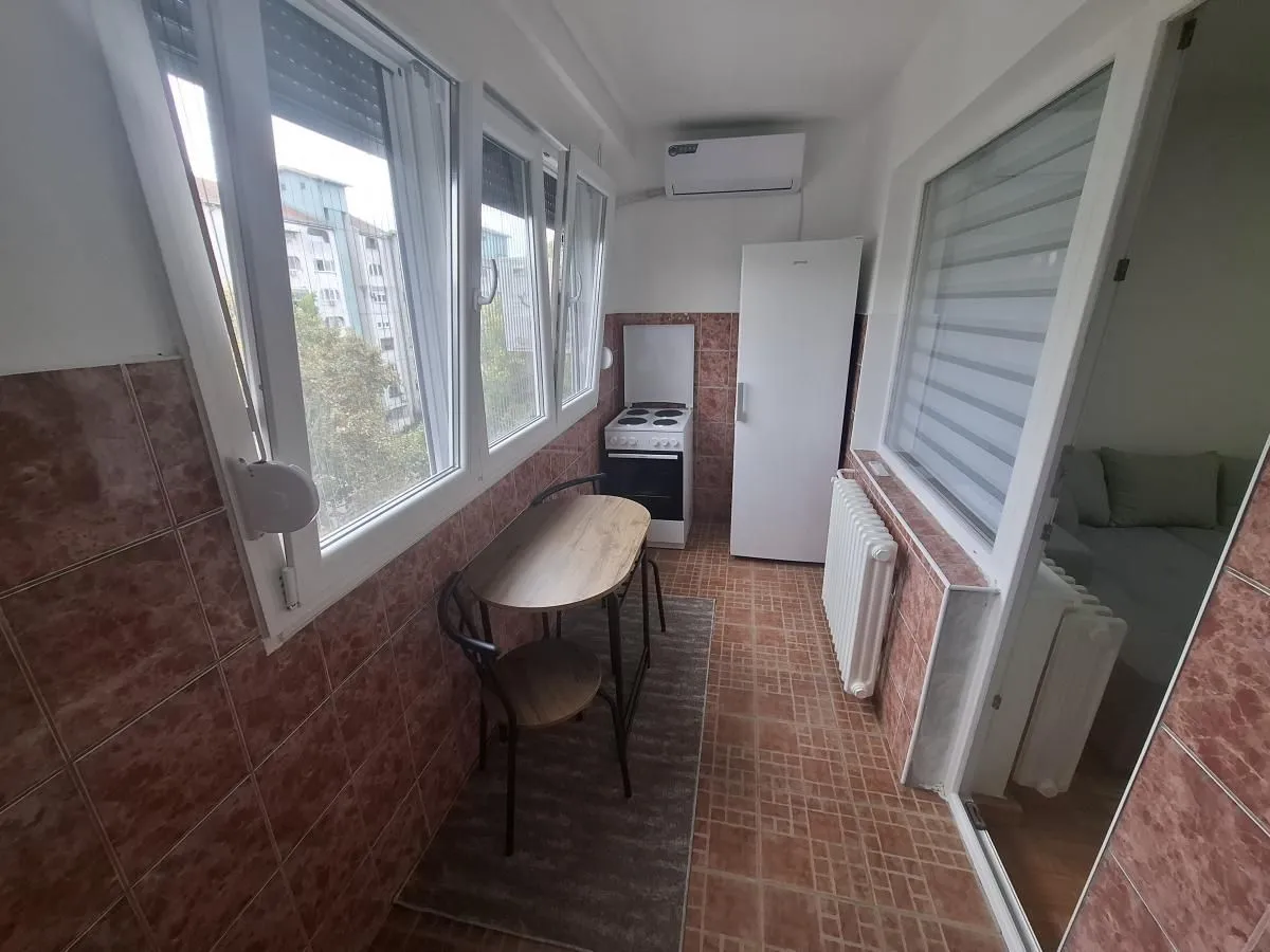 Enclosed balcony with a dining table and a small kitchenette.
