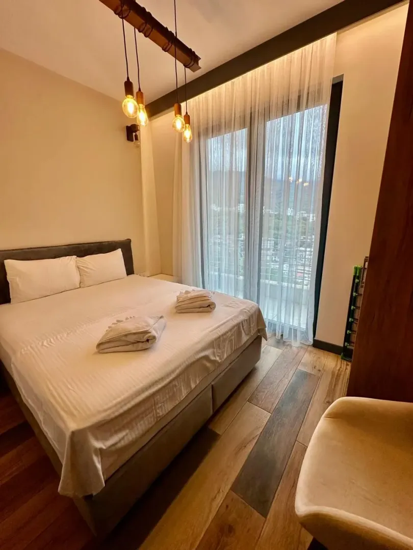 Modern bedroom with a double bed, wooden flooring, and balcony access.