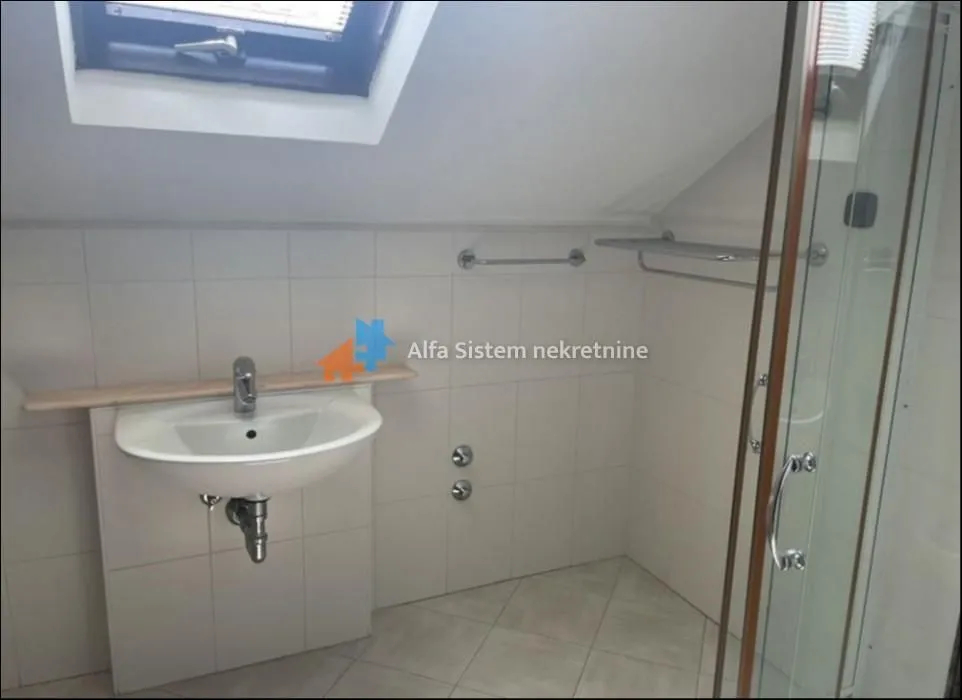 Bathroom with a washbasin and a shower cabin in the attic.