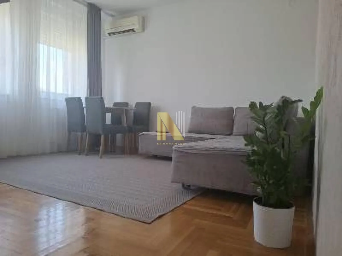 Dnevna soba sa garniturom, trpezarijskim stolom i parketom na podu.