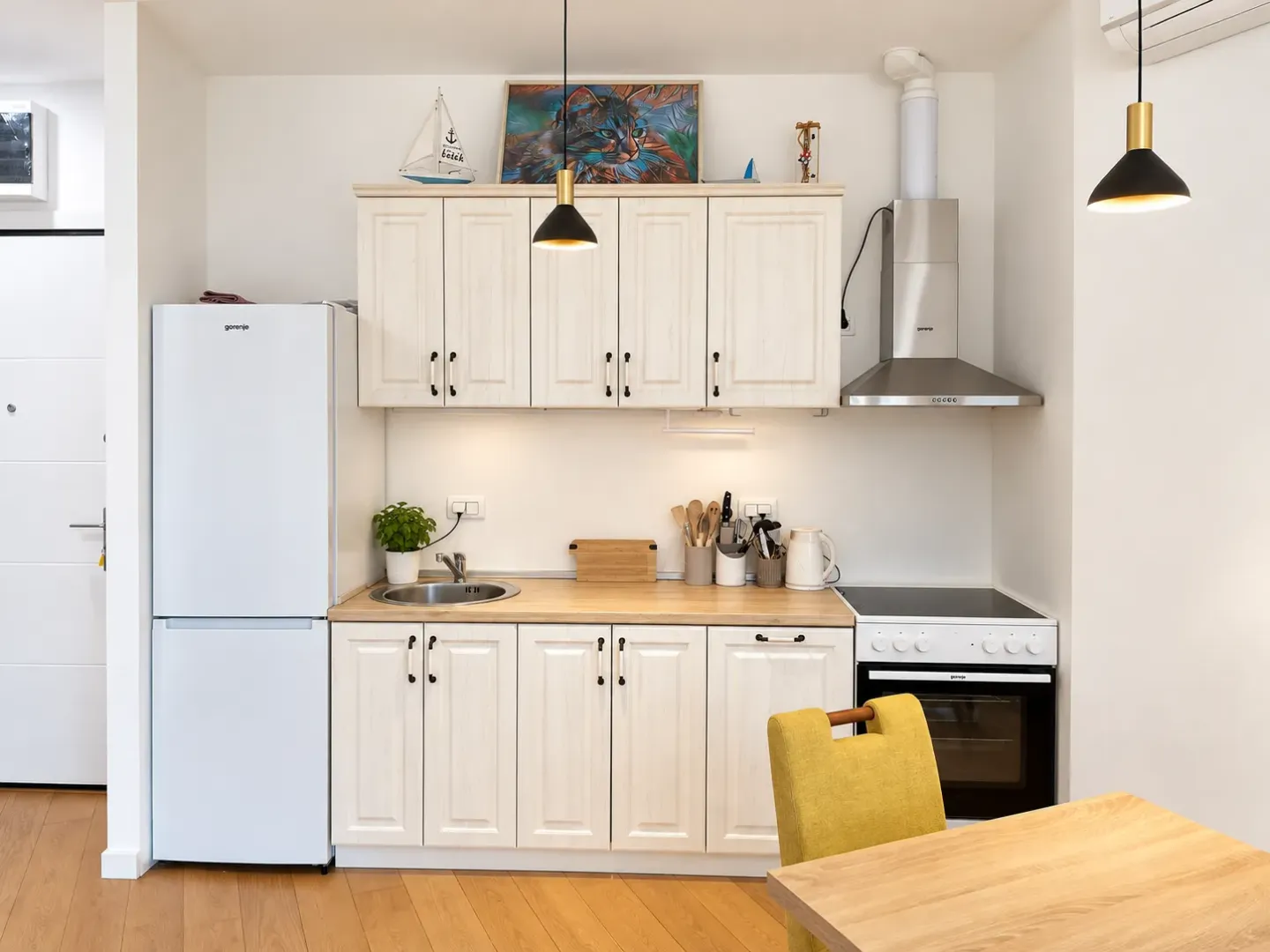 Small bright kitchen with white cabinets, refrigerator, and stove.