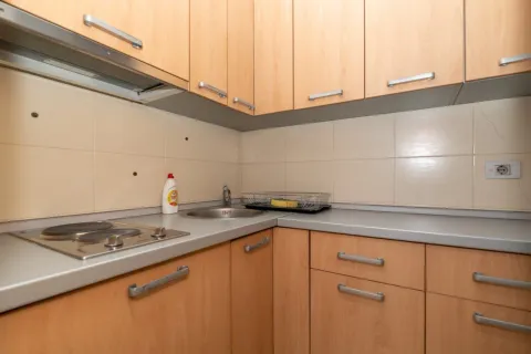 Small kitchen with light wood cabinets and a built-in cooktop. - image 8