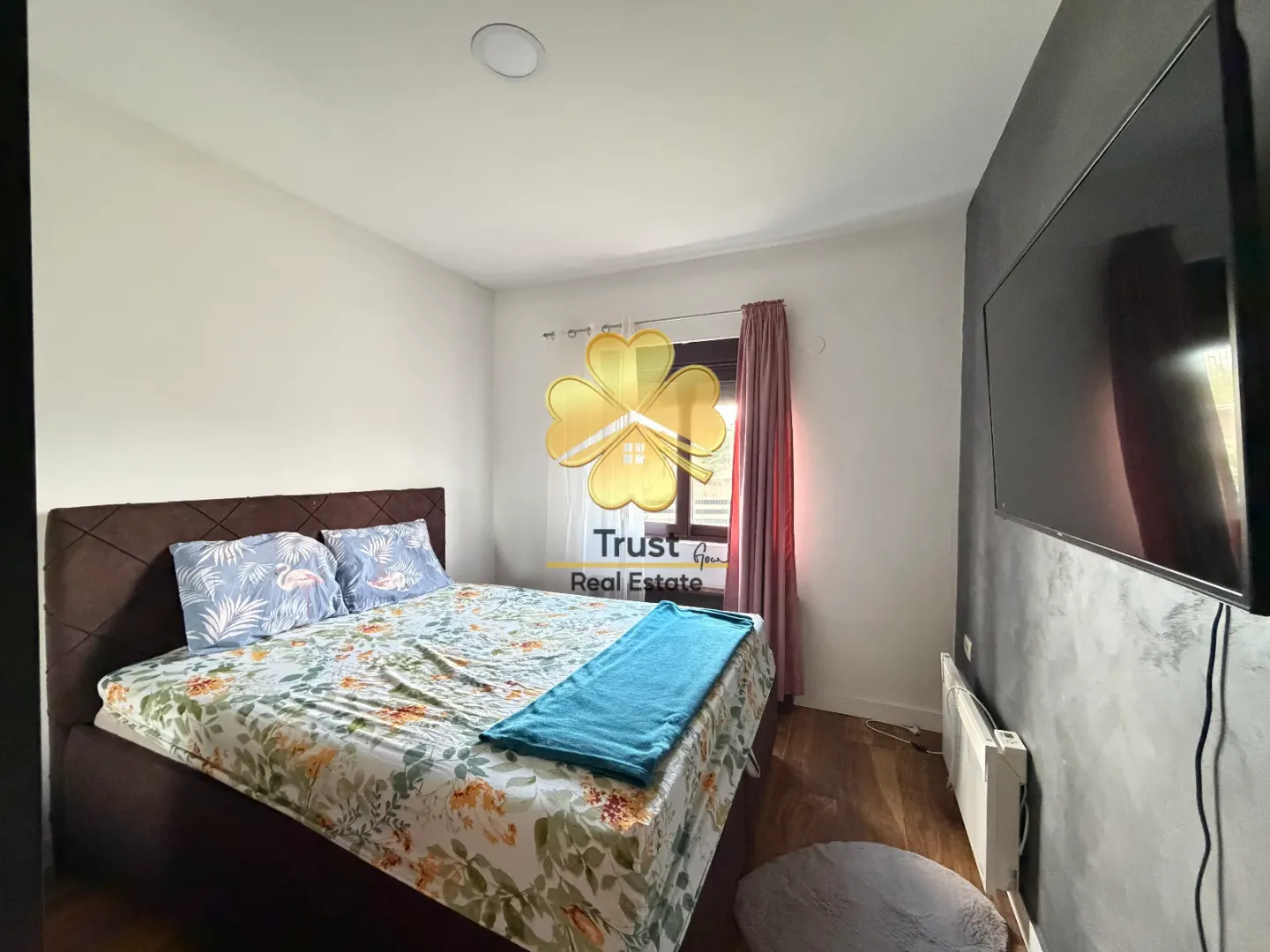 Furnished bedroom with a double bed and a wall-mounted TV.