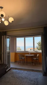 Pogled iz dnevne sobe na terasu sa garniturom za sedenje i pogledom na more. - image 3