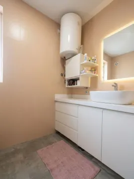 Modern bathroom with a washbasin, white cabinet, and water heater. - image 5