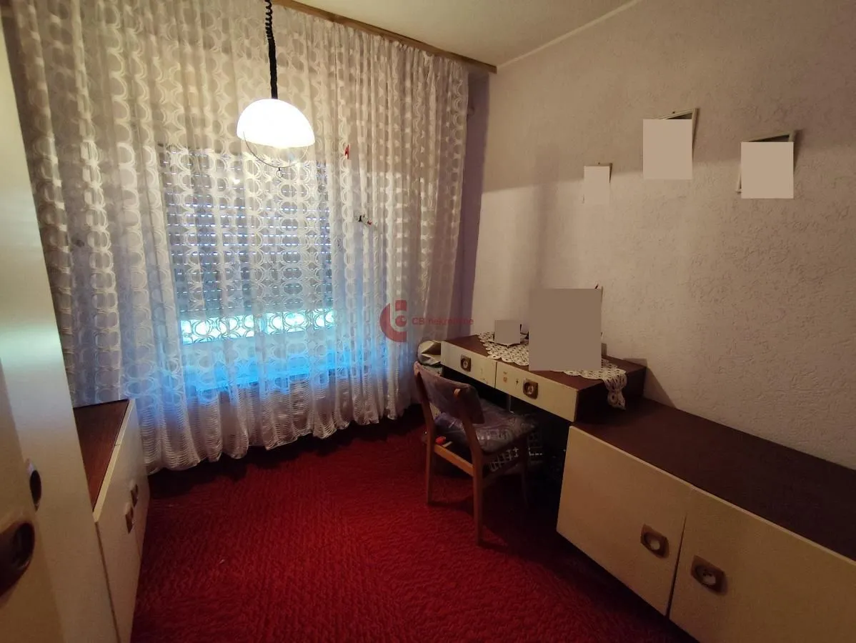 Small bedroom with a bed, desk, and window with curtains.