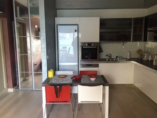Svijetla kuhinja sa trpezarijskim stolom i ugradnim uređajima.