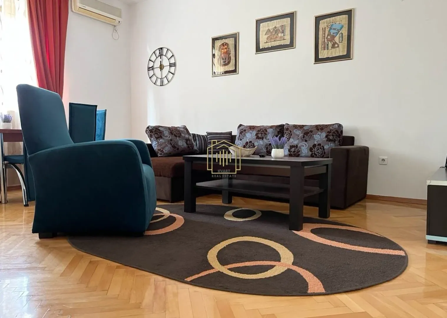 Dnevna soba sa garniturom, stočićem i tepihom na podu.