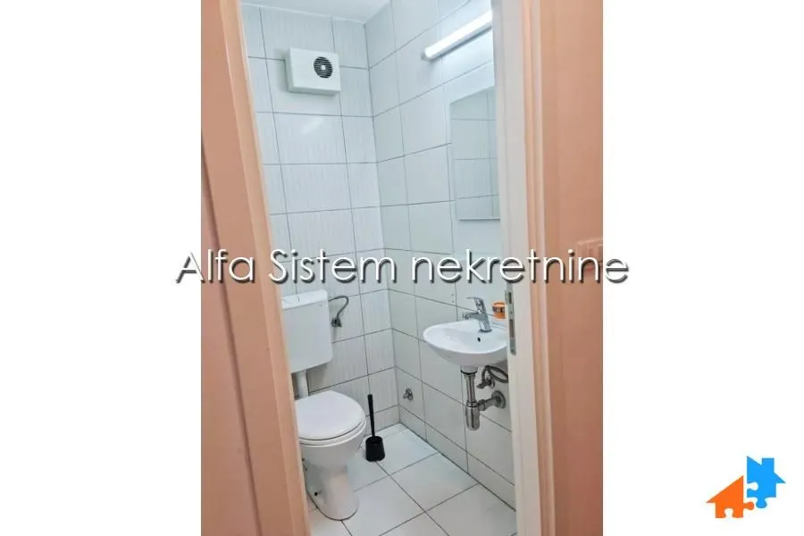 Smaller bathroom with white tiles, toilet, and washbasin.