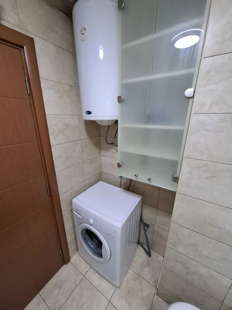 Part of a bathroom with a washing machine, boiler, and wall cabinet.