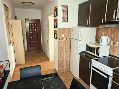 Kuhinja opremljena tamnim elementima i bijelom tehnikom sa trpezarijskim stolom u prvom planu. - image 7
