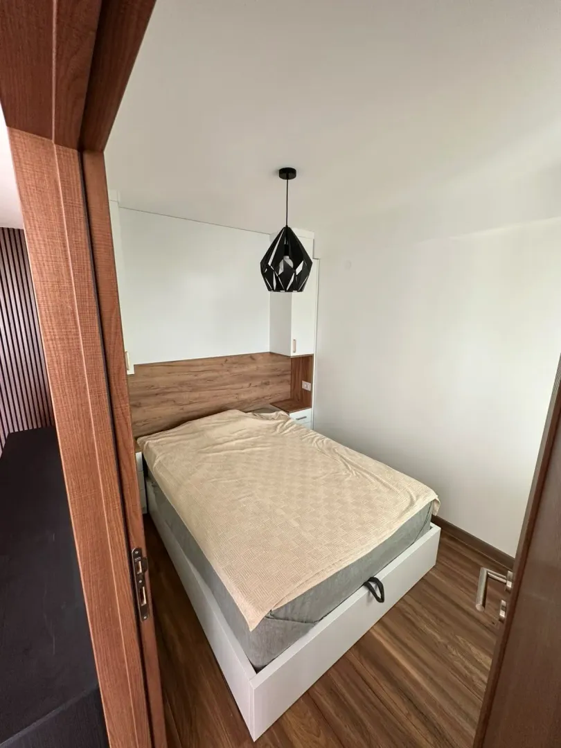 Pogled iz prolaza na nameštenu spavaću sobu sa bračnim krevetom.
