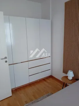 Spavaća soba sa velikim belim plakarom i drvenim panelima na zidu. - image 5