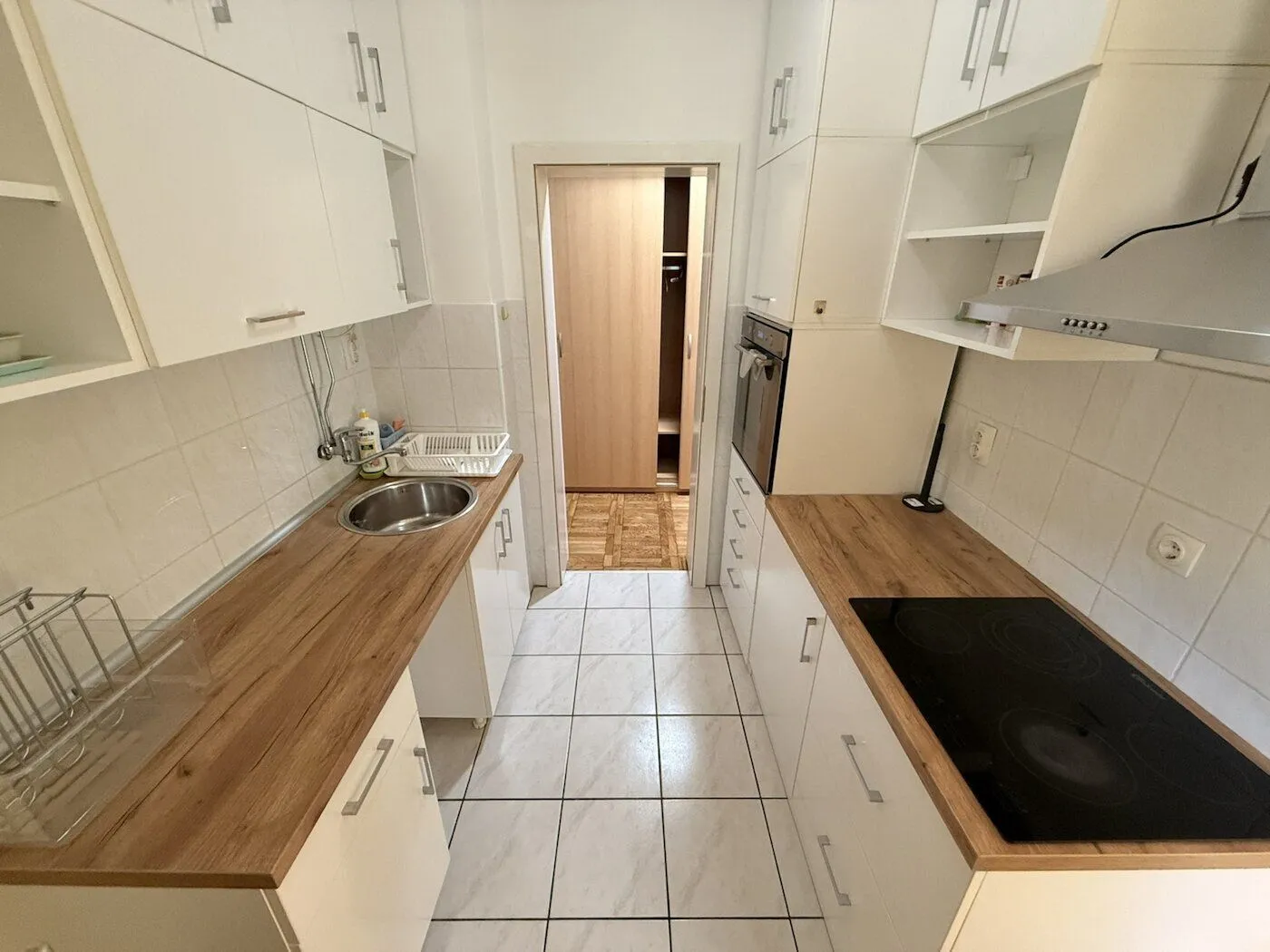 Compact white kitchen with a wooden countertop and built-in appliances.