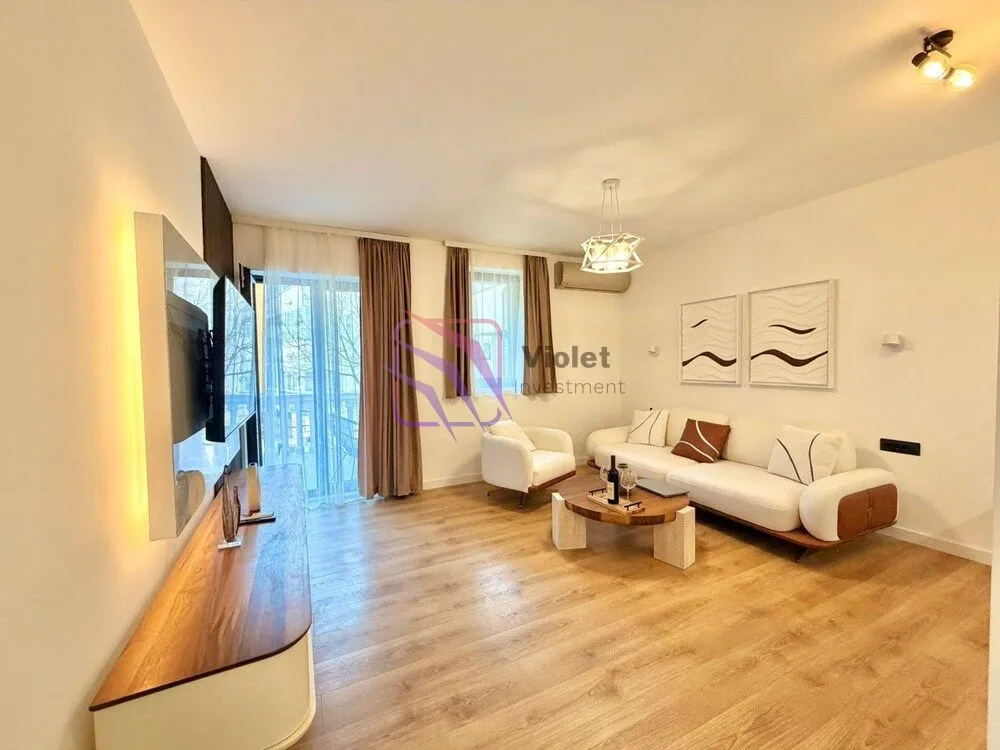 Spacious living room with sofa set, wooden flooring, and balcony access.