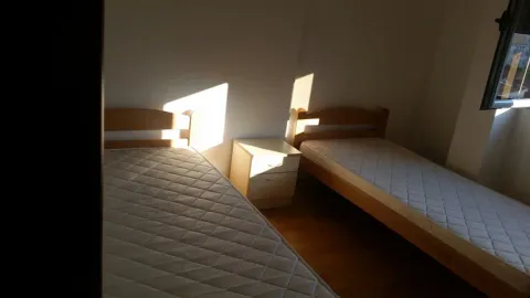 Simple bedroom featuring two single beds and a nightstand. - image 7