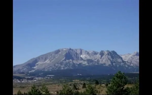 Pogled sa imanja na planinske vrhove pod vedrim nebom.