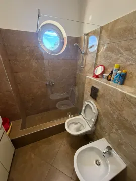 Modern bathroom with a walk-in shower, toilet, bidet, and a round window. - image 12