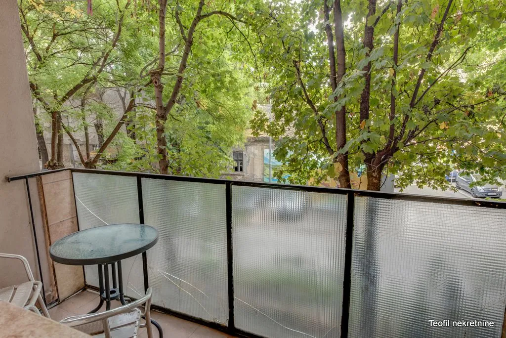 Balcony with glass railing and view of greenery and trees.