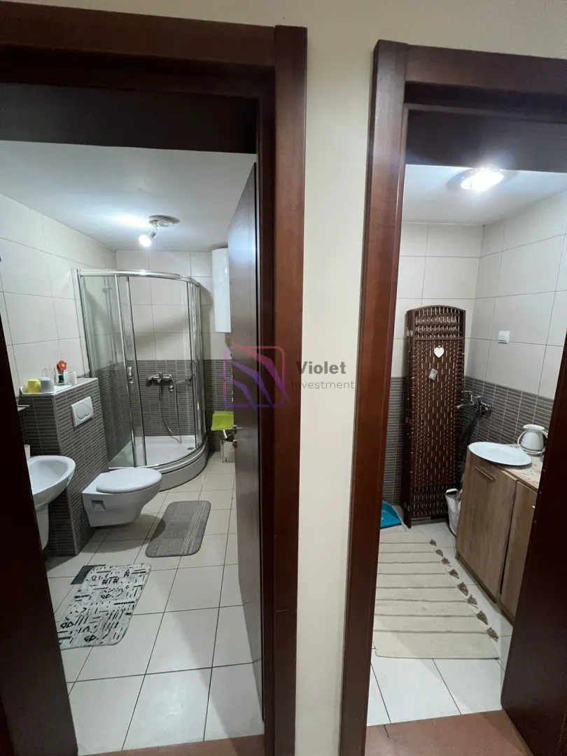 Pogled na dva kupatila sa tuš kabinom i sanitarijama kroz otvorena vrata.