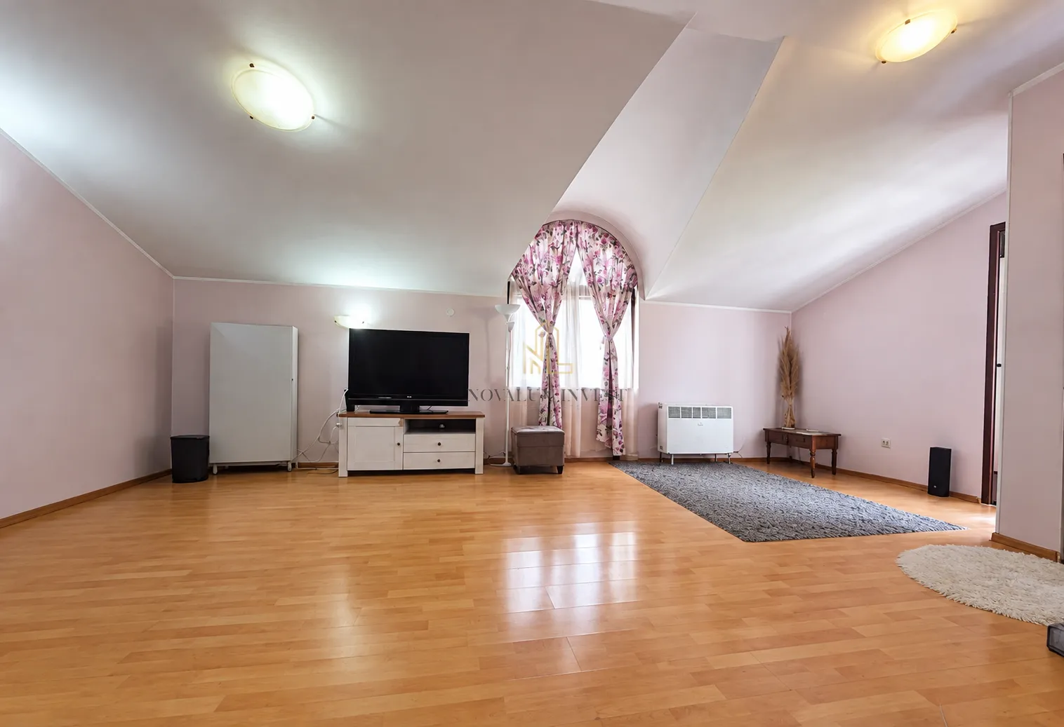 Spacious living room with sloping ceilings, TV unit and hardwood flooring.