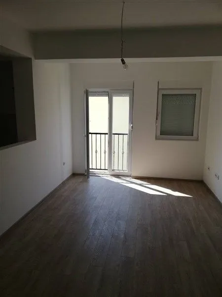 Prazna prostorija sa parketom i vratima za balkon.