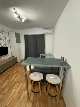 Living room with a sofa, TV, and dining table with chairs. - image 3