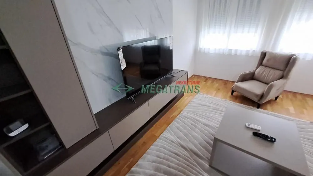 Dnevna soba sa TV komodom i foteljom.