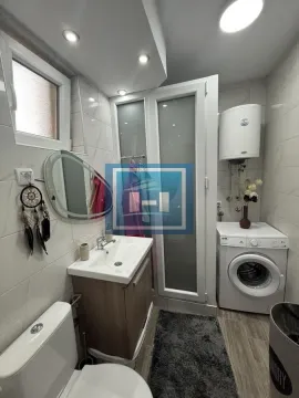 Compactly equipped bathroom with a shower cabin, washbasin, and washing machine. - image 4