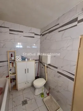 Manje kupatilo obloženo keramičkim pločicama sa toaletom, ormarićem i kadom. - image 22