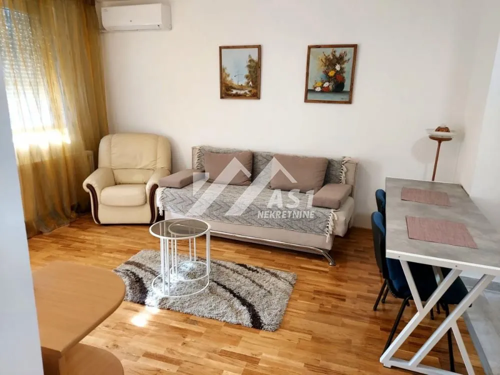 Dnevna soba sa garniturom, foteljom, stočićem i trpezarijskim stolom.