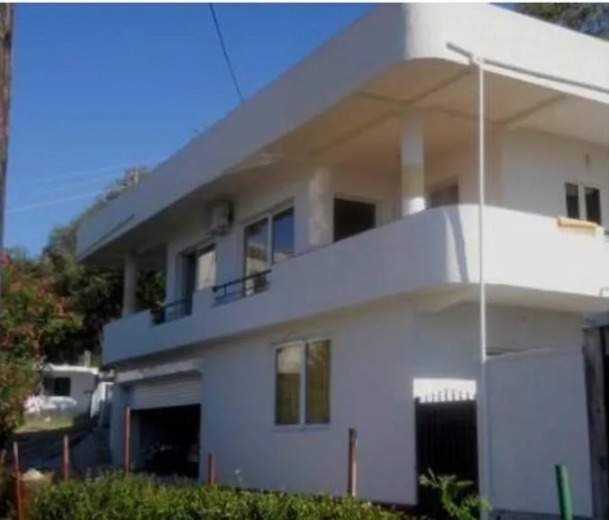 Exterior view of a two-story white house with terraces and a yard.