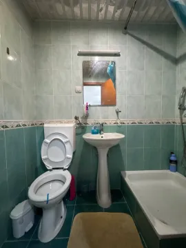 Manje kupatilo sa zelenim pločicama, umivaonikom, toaletom i tuš kadom. - image 13