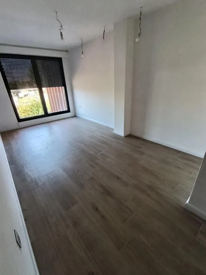 Empty unfurnished room with wooden flooring and a window.