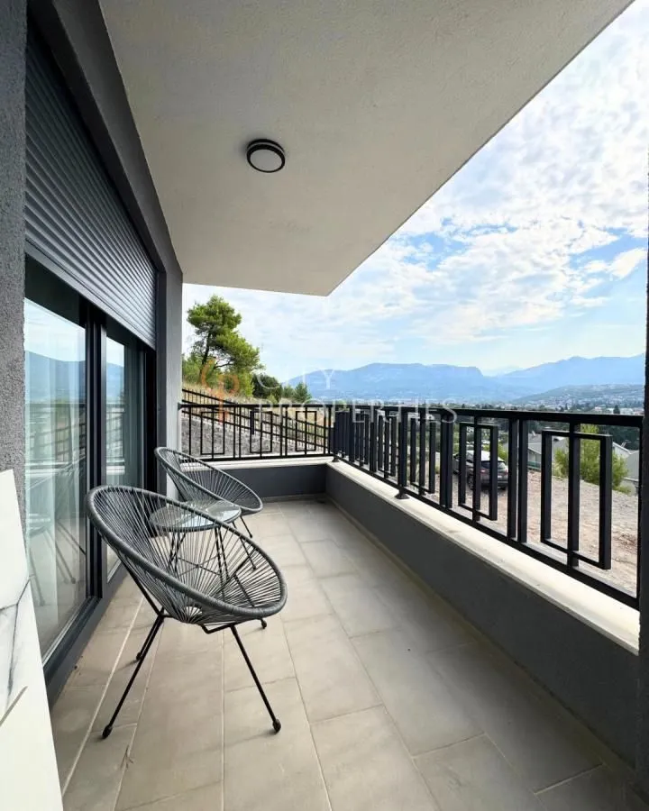 Natkriveni balkon sa garniturom za sjedenje i pogledom na planine.
