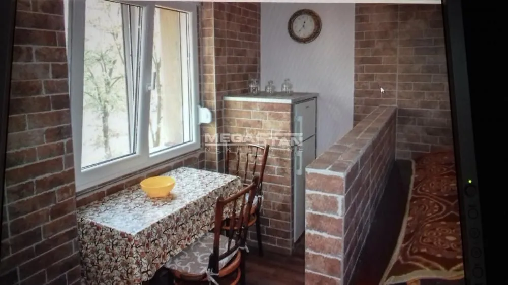 Enclosed balcony with a dining table and chairs, finished with brick cladding.