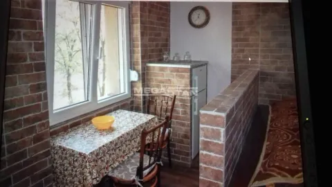 Enclosed balcony with a dining table and chairs, finished with brick cladding. - image 8