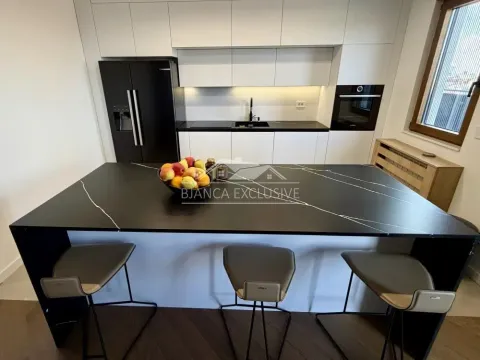 Moderna kuhinja sa belim elementima, crnim radnim površinama i ostrvom sa barskim stolicama. - image 7