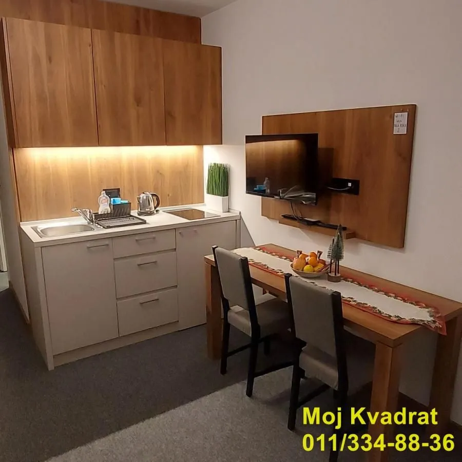 Manja kuhinja sa drvenim elementima i trpezarijskim stolom.