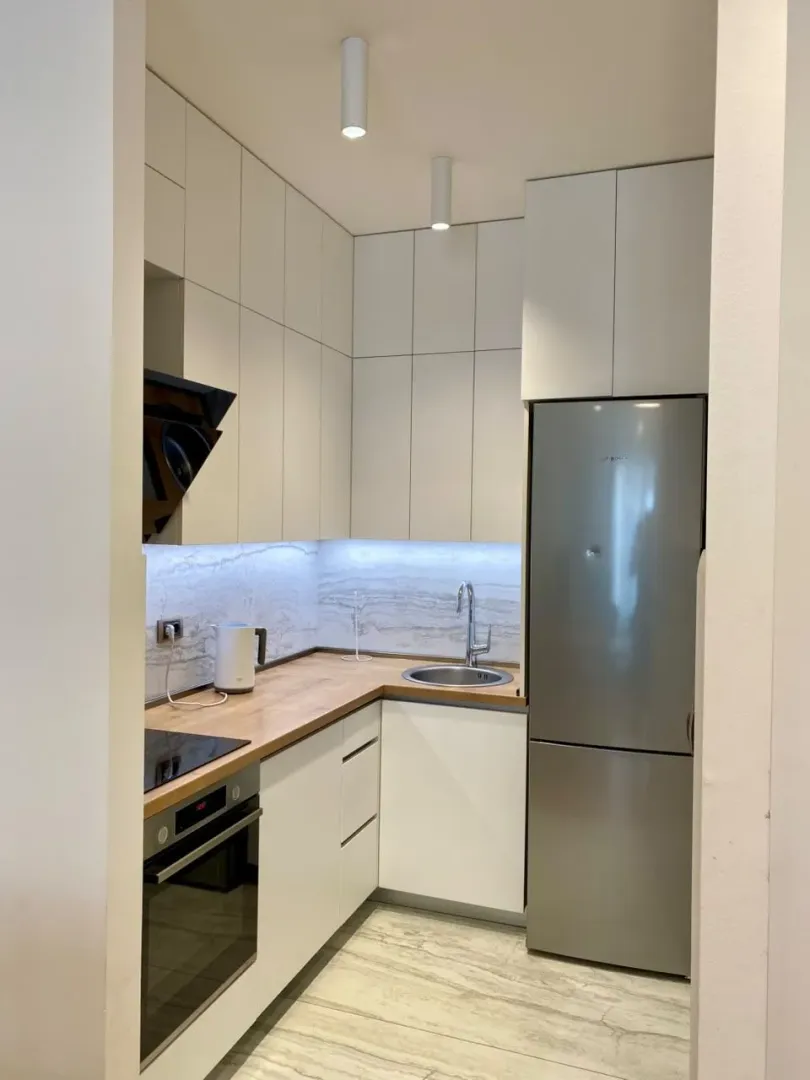 Modern white kitchen with built-in appliances and a refrigerator.