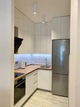 Modern white kitchen with built-in appliances and a refrigerator. - image 6