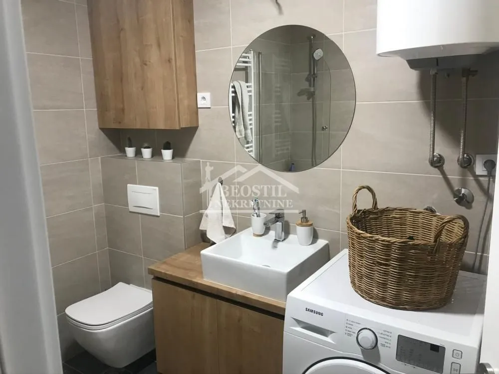 Moderno opremljeno kupatilo sa umivaonikom, WC šoljom i veš mašinom.
