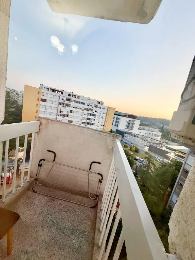 Manji balkon sa ogradom i pogledom na grad.