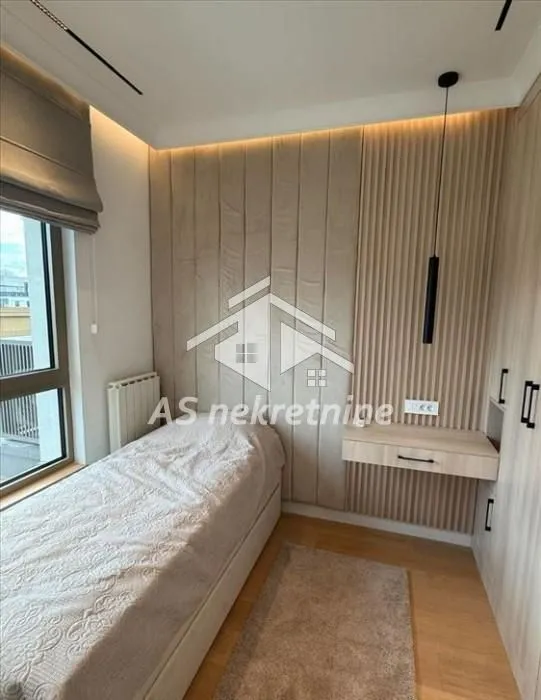 Small bedroom with a bed, built-in wardrobes, and wall panels.