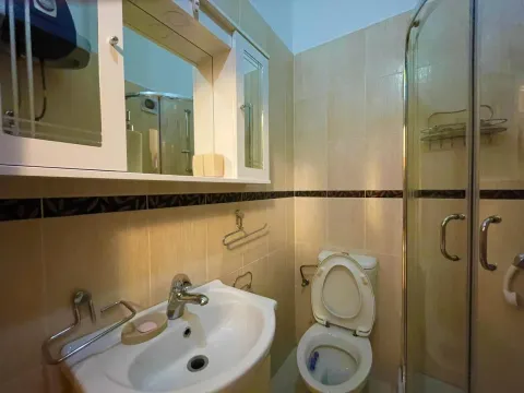 Compact bathroom with a sink, toilet, mirror, and shower enclosure. - image 7