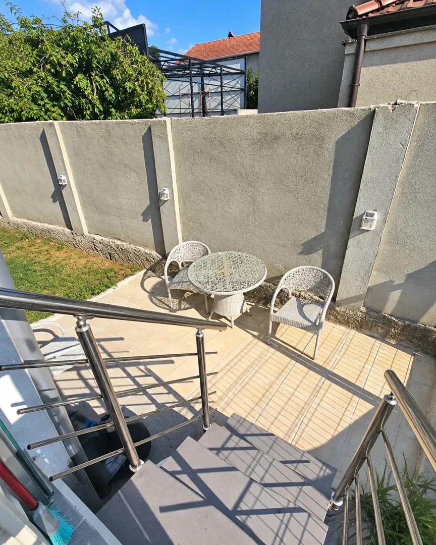 Manja popločana terasa sa garniturom za sjedenje i ogradom od nerđajućeg čelika.