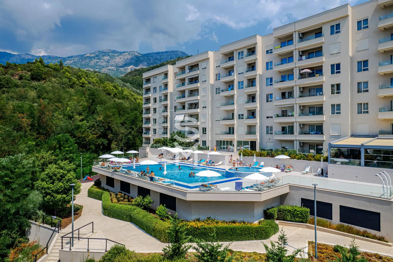 Exterior of an apartment building with a swimming pool and landscaped courtyard.